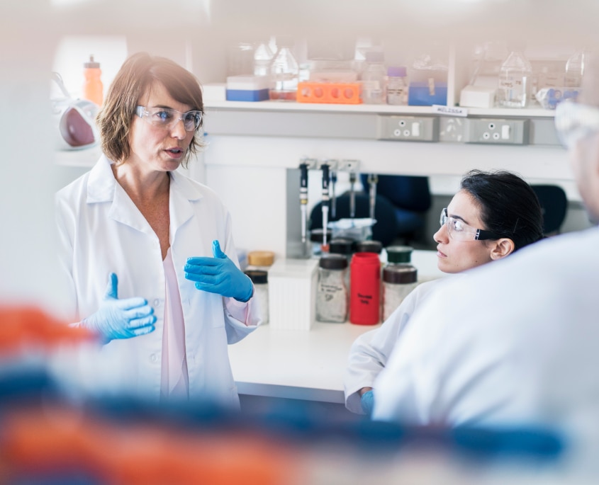 Bild på två forskare i ett labb, med vita rockar och skyddsglasögon