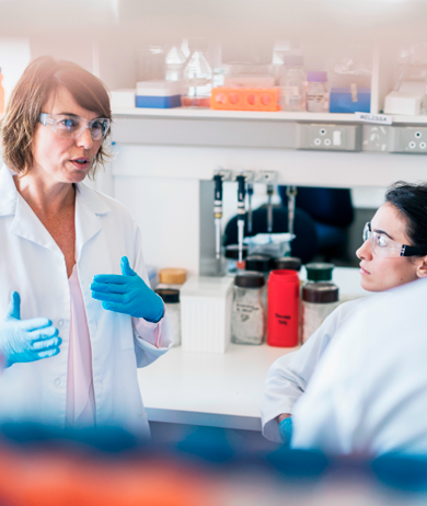 Bild på två forskare i ett labb, med vita rockar och skyddsglasögon