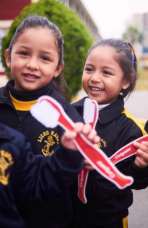 Smiling girls holding colgate toothbrushes